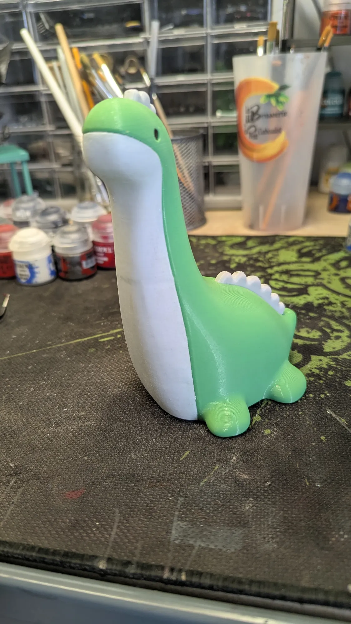 Veilleuse Nessie, monstre du Loch Ness, imprimée en PETG vert et blanc, posée sur l'établi